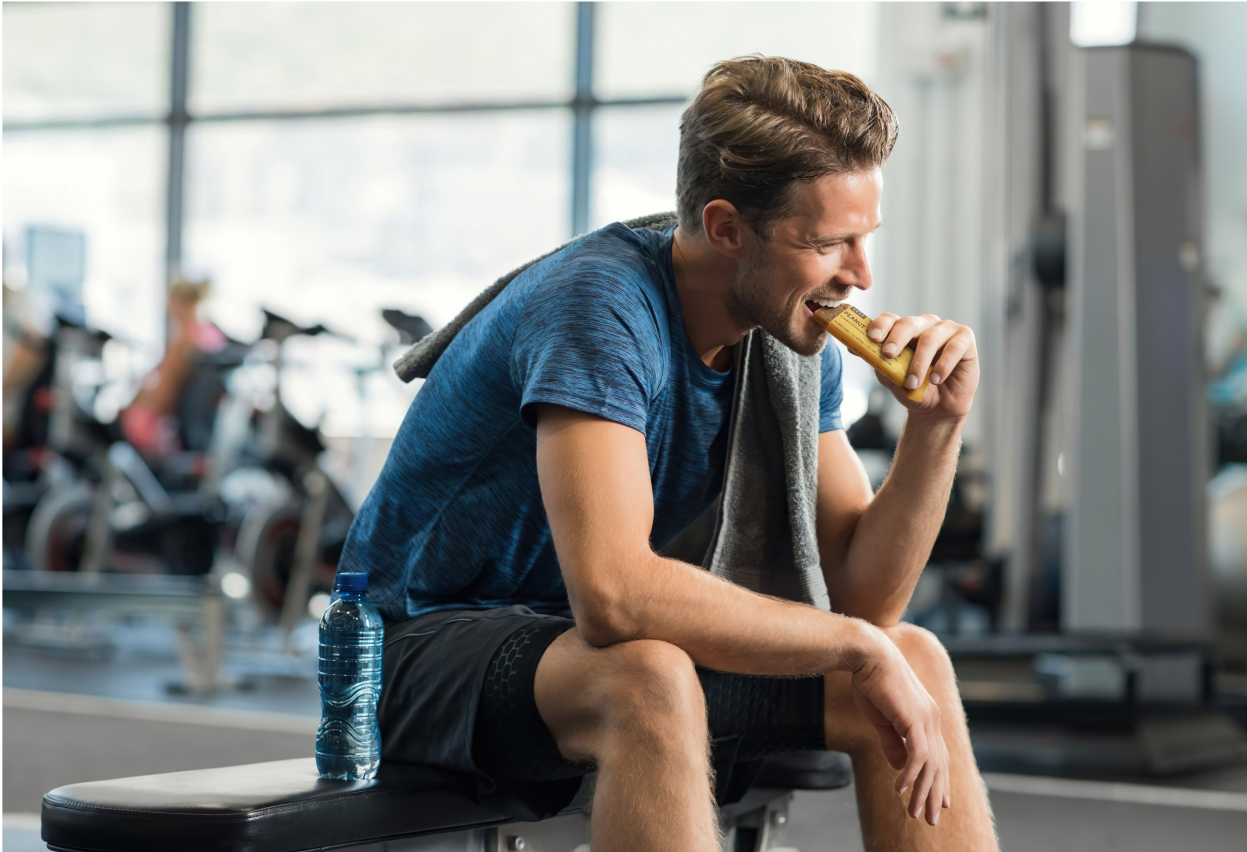 Person eating a peanut butter protein Keep bar in the gym